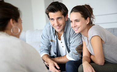 Couple Sitting on Couch Discussing Bath Remodeling Project with Designer